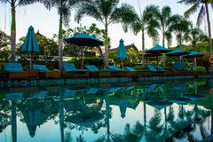 Strand sunbeds dichtbij zwembad in tropische toevlucht met palmen tijdens zonsondergang, Gili Trawangan, Lombok, Indonesië royalty-vrije stock foto Strand sunbeds dichtbij zwembad in tropische toevlucht met palmen tijdens zonsondergang, Gili Trawangan, Lombok, Indonesië royalty-vrije stock foto