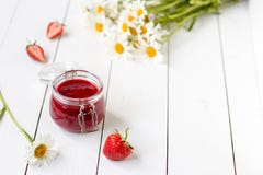 Strawberry jam in a glass jar on a table with chamomiles Royalty Free Stock Photos Strawberry jam in a glass jar on a table with chamomiles Royalty Free Stock Photos