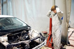Stressad mekanikerman i det vita likformiginnehavhuvudet mot bilen i reparationsgarage arkivfoton Stressad mekanikerman i det vita likformiginnehavhuvudet mot bilen i reparationsgarage arkivfoton