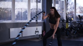 Strong muscular woman working out with battle ropes. Footage of an attractive woman in black sportswear at the gym. Slow stock video Strong muscular woman working out with battle ropes. Footage of an attractive woman in black sportswear at the gym. Slow stock video