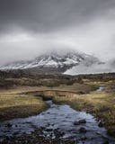 Ström som framme kör under den lilla bron av den Cotopaxi vulkan på en stormig dag royaltyfri bild Ström som framme kör under den lilla bron av den Cotopaxi vulkan på en stormig dag royaltyfri bild