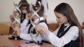 Student collegu w mundurku szkolnym studiują układ DNA i patrzeją przez mikroskopu podczas gdy siedzący w a zdjęcie wideo Student collegu w mundurku szkolnym studiują układ DNA i patrzeją przez mikroskopu podczas gdy siedzący w a zdjęcie wideo