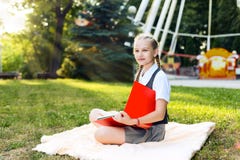 Student schoolgirl with pigtails in uniform holding books in her hands on a bright sunny day sitting on a blanket in the park royalty free stock photography Student schoolgirl with pigtails in uniform holding books in her hands on a bright sunny day sitting on a blanket in the park royalty free stock photography