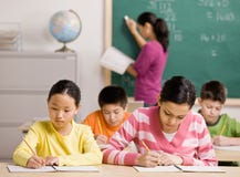 Students writing in notebook in school classroom