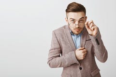 Studioskott av den roliga nerdy manliga kontorsarbetaren i moderiktigt omslag med den moderiktiga frisyren som från under ser att royaltyfri bild Studioskott av den roliga nerdy manliga kontorsarbetaren i moderiktigt omslag med den moderiktiga frisyren som från under ser att royaltyfri bild