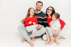 Studioskottet av lyckliga familjemedlemmar sitter på golv med kal fot, arkivfoton Studioskottet av lyckliga familjemedlemmar sitter på golv med kal fot, arkivfoton