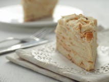 Stuk van multi gelaagd cakeclose-up Mille feuille dessert Verkruimelt verfraaid torte op witte doily op houten lijst royalty-vrije stock afbeeldingen Stuk van multi gelaagd cakeclose-up Mille feuille dessert Verkruimelt verfraaid torte op witte doily op houten lijst royalty-vrije stock afbeeldingen