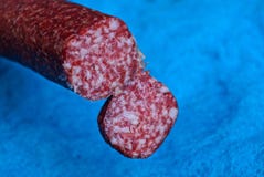 Stuk van rode salamiworst op blauwe achtergrond royalty-vrije stock afbeeldingen Stuk van rode salamiworst op blauwe achtergrond royalty-vrije stock afbeeldingen