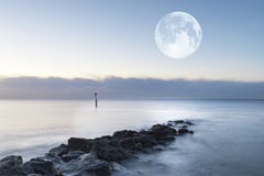 Stunning sunrise landscape over rocks in sea with super moon Royalty Free Stock Photo Stunning sunrise landscape over rocks in sea with super moon Royalty Free Stock Photo