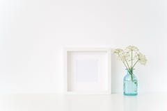 Cute white square frame mock up with a Aegopodium in transparent blue vase. Mockup for quote, promotion, headline