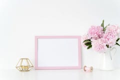Pink landscape frame mock up with a pink peonies, candle and silk ribbons beside the frame, overlay your quote