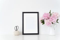 White portrait frame mock up with a pink peonies beside the frame, overlay your quote, promotion, headline, or design
