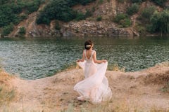 Stylish, beautiful bride posing in a luxurious dress against the backdrop of a sunset and a river. Photo from the back royalty free stock image Stylish, beautiful bride posing in a luxurious dress against the backdrop of a sunset and a river. Photo from the back royalty free stock image