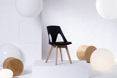 Stylish black chair on white platform in bright showroom interior with big balloons and wooden blocks