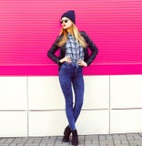 Stylish blonde woman model in full-length posing wearing rock black style jacket, hat on city street over colorful pink wall royalty free stock images Stylish blonde woman model in full-length posing wearing rock black style jacket, hat on city street over colorful pink wall royalty free stock images