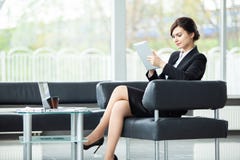 Stylish businesswoman sitting on sofa using tablet pc in the office. stock photo Stylish businesswoman sitting on sofa using tablet pc in the office. stock photo