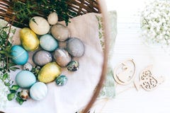Stylish Easter Eggs And Green Buxus Branches In Wicker Basket On White Wooden Background With Simple Wood Bunny And Chicken Stock Photo Stylish Easter Eggs And Green Buxus Branches In Wicker Basket On White Wooden Background With Simple Wood Bunny And Chicken Stock Photo