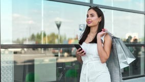Stylish female model enjoying shopping using smartphone walking outdoor steadicam establish shot