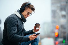 Stylish guy in headset using his mobile phone outdoors Stock Image Stylish guy in headset using his mobile phone outdoors Stock Image