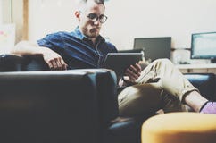 Stylish Hipster working digital tablet modern Interior Design Loft Office.Man work Vintage Sofa electronic device. Sunny Blurred Background.Creative Process stock images Stylish Hipster working digital tablet modern Interior Design Loft Office.Man work Vintage Sofa electronic device. Sunny Blurred Background.Creative Process stock images