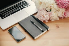Stylish laptop, phone with empty screen, black notebook, peonies on rustic wooden table. Freelance concept.Space for text. stock photos Stylish laptop, phone with empty screen, black notebook, peonies on rustic wooden table. Freelance concept.Space for text. stock photos
