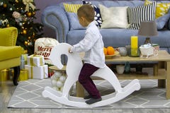 Stylish little boy ride on a rocking horse in room with modern desing. Christmas stock image Stylish little boy ride on a rocking horse in room with modern desing. Christmas stock image