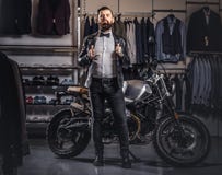 Stylish tattooed bearded man with dressed in black leather jacket and bow tie posing near retro sports motorbike at men royalty free stock images Stylish tattooed bearded man with dressed in black leather jacket and bow tie posing near retro sports motorbike at men royalty free stock images