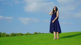 A stylish woman in a hat and sunglasses waiting for a child. Standing on a green meadow against a blue sky background stock video A stylish woman in a hat and sunglasses waiting for a child. Standing on a green meadow against a blue sky background stock video