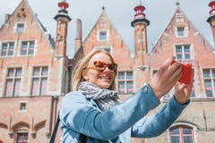 Stylish young female tourist takes a selfie on a mobile phone in Bruges, Belgium. stock images Stylish young female tourist takes a selfie on a mobile phone in Bruges, Belgium. stock images