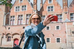Stylish young female tourist takes a selfie on a mobile phone in Bruges, Belgium. royalty free stock image Stylish young female tourist takes a selfie on a mobile phone in Bruges, Belgium. royalty free stock image