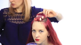Styliste féminin créant la coiffure parfaite avec de grandes boucles pour la jeune femme rousse Styliste féminin créant la coiffure parfaite avec de grandes boucles pour la jeune femme rousse