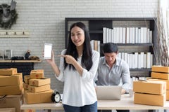 Stående av att le den asiatiska hållsmartphonen för ung kvinna med att stå för kartonger royaltyfria foton Stående av att le den asiatiska hållsmartphonen för ung kvinna med att stå för kartonger royaltyfria foton