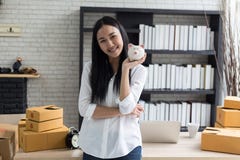 Stående av att le den asiatiska unga kvinnan med att stå för spargris och för kartonger royaltyfri bild Stående av att le den asiatiska unga kvinnan med att stå för spargris och för kartonger royaltyfri bild