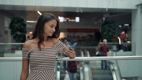 Stående av att le kvinnan som använder smartphonestämmaerkännande Ung Caucasian flicka i flygplatsterminal med bagage lager videofilmer Stående av att le kvinnan som använder smartphonestämmaerkännande Ung Caucasian flicka i flygplatsterminal med bagage lager videofilmer