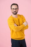 Stående av den attraktiva mannen med korsningen händer på bröstkorg i ockrakofta och exponeringsglas på rosa bakgrund royaltyfria bilder Stående av den attraktiva mannen med korsningen händer på bröstkorg i ockrakofta och exponeringsglas på rosa bakgrund royaltyfria bilder
