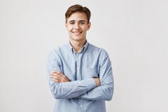 Stående av den stiliga unga mannen i tillfällig blå skjorta Pojken ler för kameran som uttrycker lycka och glädje Hans gulligt arkivfoton Stående av den stiliga unga mannen i tillfällig blå skjorta Pojken ler för kameran som uttrycker lycka och glädje Hans gulligt arkivfoton