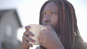 Stående av den unga svarta le kvinnan för nätt säker afrikansk amerikan med den varma koppen kaffe på gatan långsamt lager videofilmer Stående av den unga svarta le kvinnan för nätt säker afrikansk amerikan med den varma koppen kaffe på gatan långsamt lager videofilmer