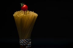 Stående av packad modespagetti som överst binds med bandet på mörk bakgrund med tomaten arkivbild Stående av packad modespagetti som överst binds med bandet på mörk bakgrund med tomaten arkivbild