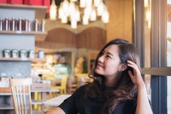 Ståendebild av en härlig asiatisk kvinna för smiley med mening bra av sitta och av att koppla av i modernt kafé arkivbild Ståendebild av en härlig asiatisk kvinna för smiley med mening bra av sitta och av att koppla av i modernt kafé arkivbild