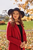 Ståenden av en aristokratisk flicka som går i en höst, parkerar i ett rött lag och en svart hatt arkivfoto Ståenden av en aristokratisk flicka som går i en höst, parkerar i ett rött lag och en svart hatt arkivfoto