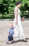 Ståenden av en härlig ung kvinnlig brud som går med litet, behandla som ett barn pojken till bröllopceremoni Fostra och hennes li arkivfoton Ståenden av en härlig ung kvinnlig brud som går med litet, behandla som ett barn pojken till bröllopceremoni Fostra och hennes li arkivfoton