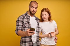 Ståenden av ett ungt paranseende med mobiltelefonen, man använder mobiltelefonen medan det ilskna flickaanseendet nära isolerat ö royaltyfri fotografi Ståenden av ett ungt paranseende med mobiltelefonen, man använder mobiltelefonen medan det ilskna flickaanseendet nära isolerat ö royaltyfri fotografi