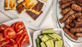 Stół z piec na grillu cevapcici pomidorami i ogórkami obraz stock Stół z piec na grillu cevapcici pomidorami i ogórkami obraz stock