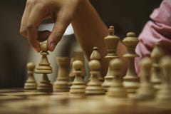 Su un gioco di scacchi, un giocatore di scacchi fa un movimento con un pegno immagine stock libera da diritti Su un gioco di scacchi, un giocatore di scacchi fa un movimento con un pegno immagine stock libera da diritti