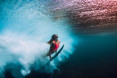 Submarino deportivo de la zambullida de la mujer de la persona que practica surf con la onda inferior del barril foto de archivo Submarino deportivo de la zambullida de la mujer de la persona que practica surf con la onda inferior del barril foto de archivo