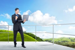 Successful asian businessman standing with laptop on the terrace royalty free stock photos Successful asian businessman standing with laptop on the terrace royalty free stock photos