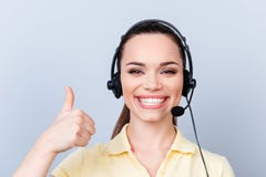Successful young brunette girl in headset on a pure light background, wearing casual yellow tshirt, smiling and showing thumbup s stock images Successful young brunette girl in headset on a pure light background, wearing casual yellow tshirt, smiling and showing thumbup s stock images