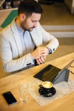 Successful young businessman looking at his watch, working in cafe stock photo Successful young businessman looking at his watch, working in cafe stock photo