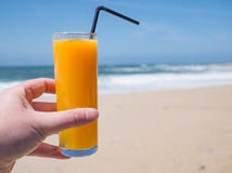 Succo d'arancia fresco sulla spiaggia sabbiosa dorata con cielo blu immagini stock Succo d'arancia fresco sulla spiaggia sabbiosa dorata con cielo blu immagini stock