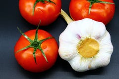 Succoso dei pomodori e fresco rossi nella società di aglio solo su un fondo nero fotografia stock libera da diritti Succoso dei pomodori e fresco rossi nella società di aglio solo su un fondo nero fotografia stock libera da diritti